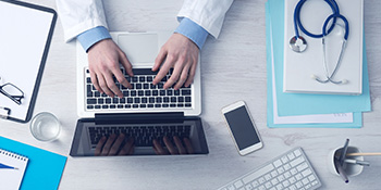 Doctor sending email at his desk